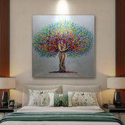 A hand-painted, colorful artwork of a tree with a couple embracing, displayed on a wall in a room with two lamps and a bed.