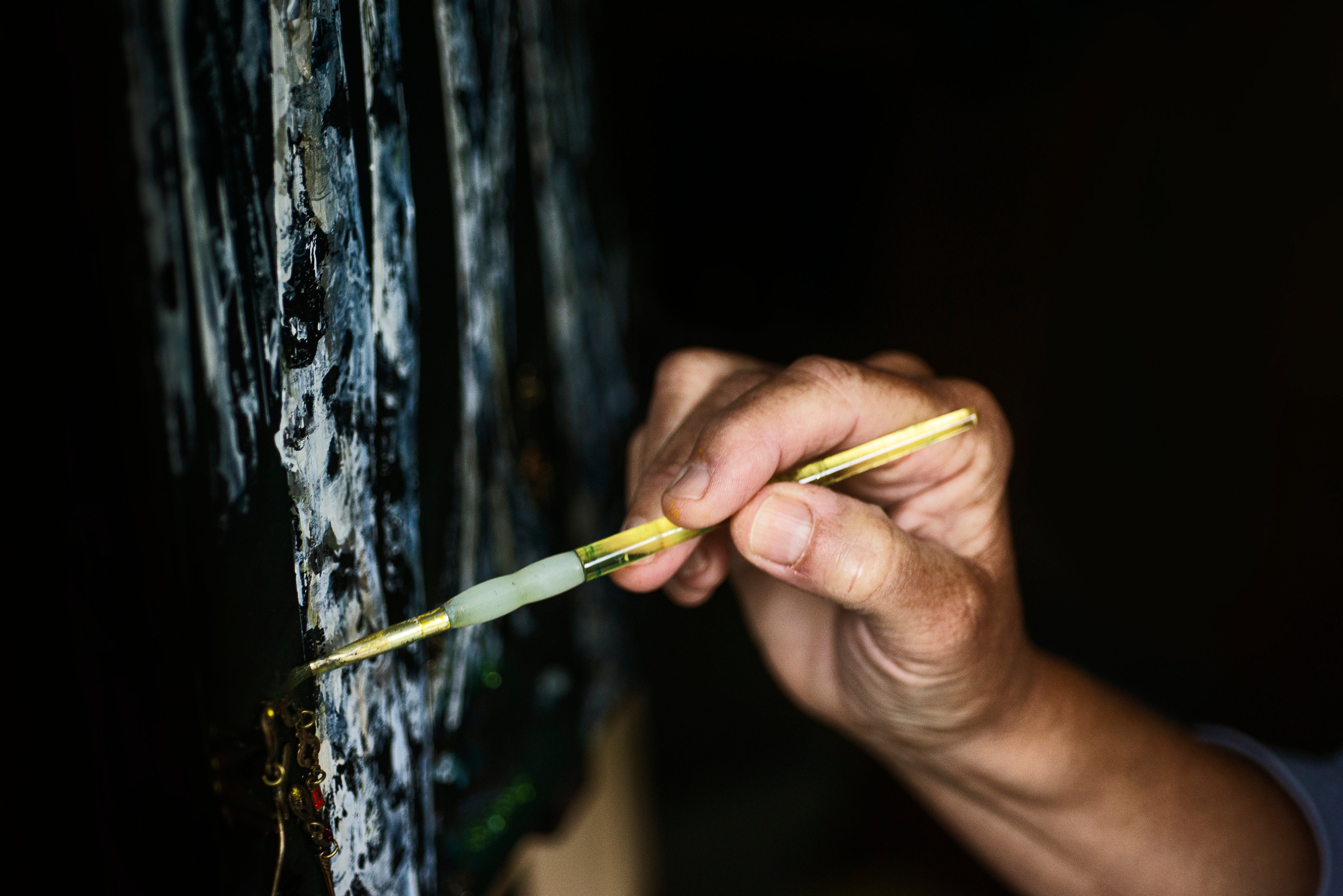 hand-holds-a-yellow-paint-brush-to-a-painting-of-trees.jpg