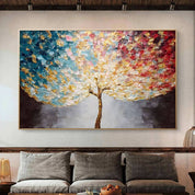 Colorful abstract tree painting on a wall above a gray sofa in a living room.
