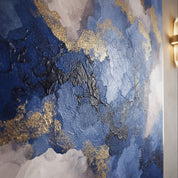 Abstract art piece with blue, gold, and gray colors on a textured surface.