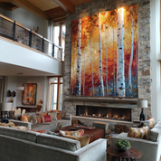 Modern living room with a large abstract painting of trees above a fireplace.